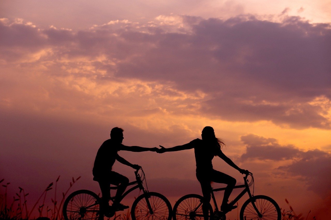 Two people on bikes are a partnership holding hands for a strong relationship